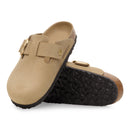 Pair of beige clogs with gold buckles on a white background