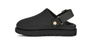 A black clog-style sandal with a wide adjustable strap and a small gold-tone snap button, shown from a side profile on a white background.
