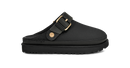 A black slip-on clog-style shoe with a wide strap and a gold-tone buckle, shown in a side profile on a plain white background.