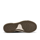 The outsole view of a Clarks shoe, showing a dark brown treaded rubber sole with a cream-colored inner arch area and the Clarks logo printed in gold.