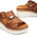 Brown sandals with a white sole on a light gray background