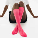 Person wearing pink striped knee-high socks on a white background