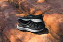 A pair of black and white Kipsta slip-on shoes resting on textured orange-brown rocks outdoors.